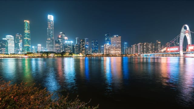A vibrant view of Guangzhou's illuminated skyline reflecting over the Pearl River at night.