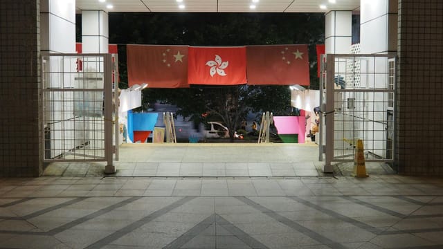 A nighttime view of a Hong Kong entrance with hanging flags prominently displayed.