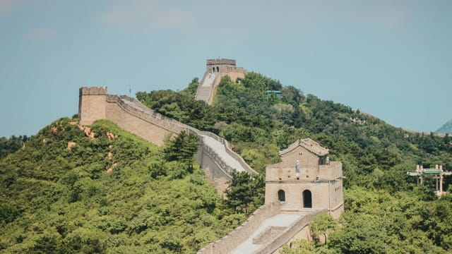 Explore the historic architecture of the Great Wall of China surrounded by lush greenery.