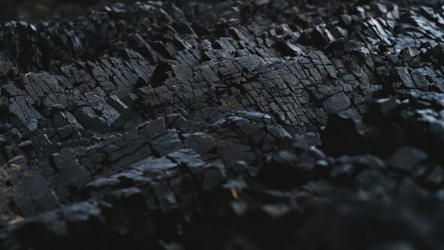 A detailed close-up of dark charcoal texture, showcasing its rough and jagged surface.