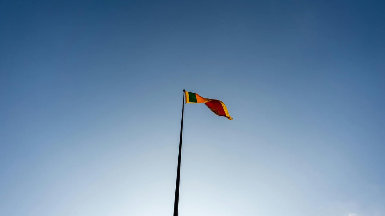 A majestic view of the Sri Lankan flag waving against a clear blue sky in Colombo.