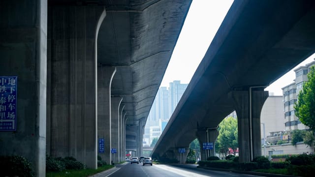 A modern urban highway underpass with clear traffic lanes and city buildings in the background.