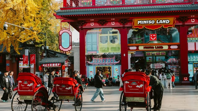 Capture of a bustling street scene in Nanjing with rickshaws and autumn colors in full display.