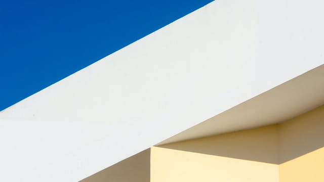 Minimalist architectural design featuring geometric forms against a clear blue sky.