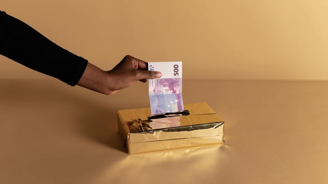Euro banknote held by a hand against beige background, symbolizing bribery or gifting.