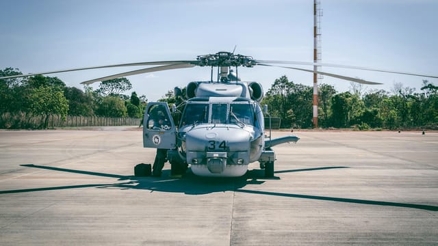 Military helicopter parked outdoors on a sunny day at a Brazilian airfield.
