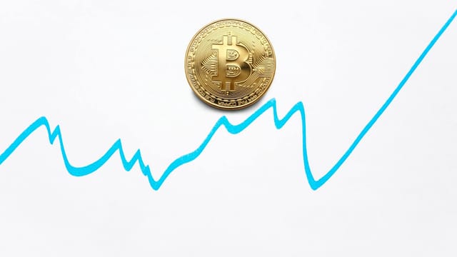 Gold bitcoin cryptocurrency coin and blue graph of changes of value on white background
