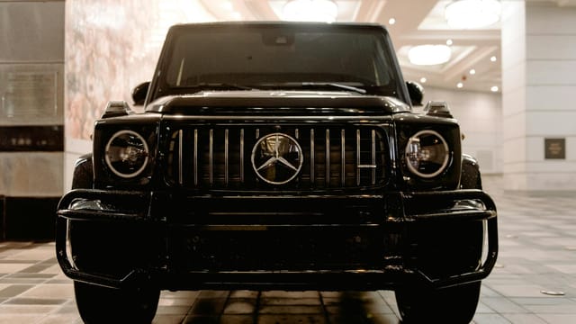 Modern black SUV automobile parked on tiled floor on underground parking with white columns and glowing lamps on ceiling