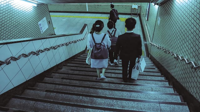 People walking down the stairs in a Tokyo subway station, showcasing urban commute.