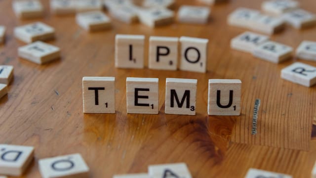 Scrabble tiles spelling IPO and Temu placed on a wooden table surface.