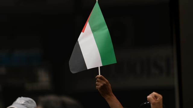 Close-up of a hand holding a Palestinian flag during protest in Rabat, Morocco.
