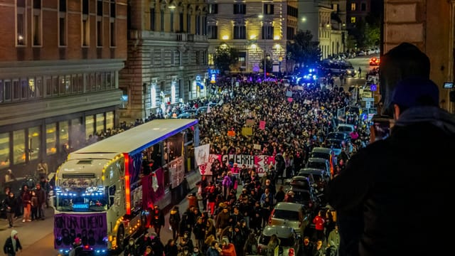 Crowded city street filled with people marching during a vibrant nighttime protest