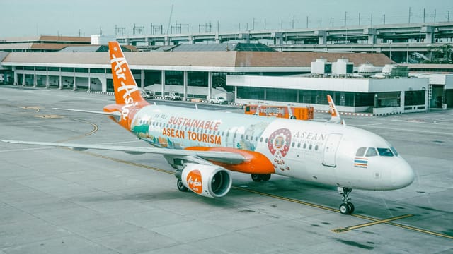 AirAsia airplane promoting sustainable ASEAN tourism parked at an airport.