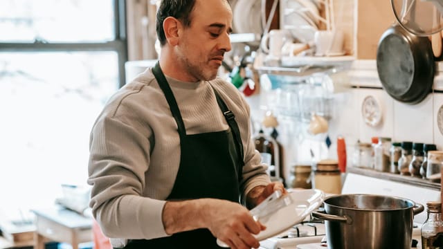 A man in a kitchen preparing a meal, showcasing home cooking and casual lifestyle.