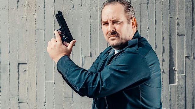 Police officer holding a firearm with a serious expression, emphasizing public safety.