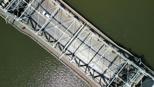 Drone shot of a steel bridge over a river in Tianjin, China, showcasing urban infrastructure.