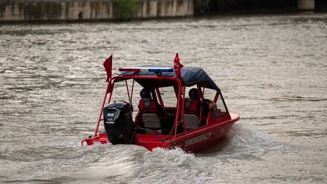 Red emergency boat navigating a river in Tbilisi, Georgia, providing water rescue services.