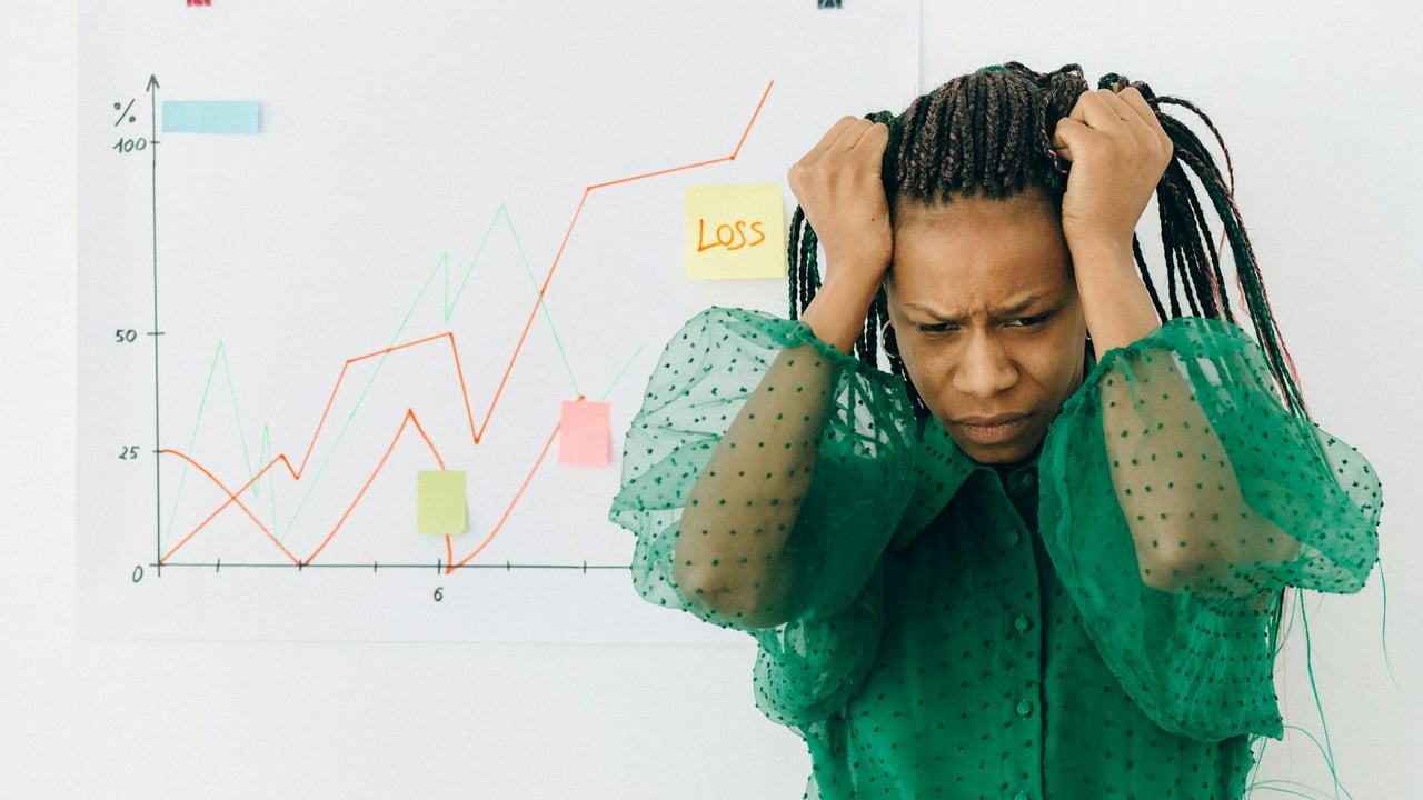 Frustrated businesswoman in green blouse analyzing a graph showing financial loss.