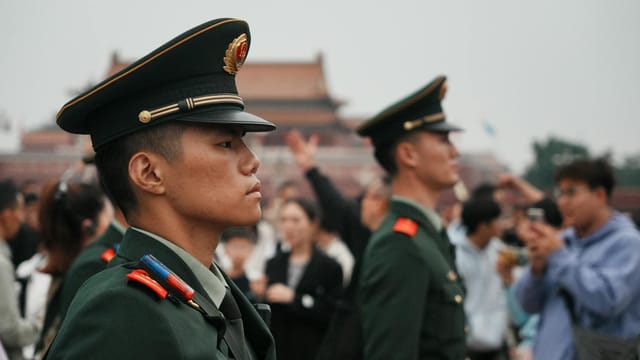 Uniformed guards stand vigil amidst a crowd at Tiananmen Square.