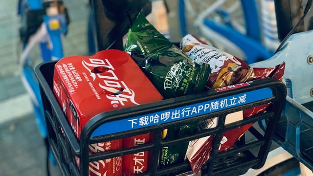 A close-up of a bicycle basket filled with snacks and drinks in urban Shanghai.