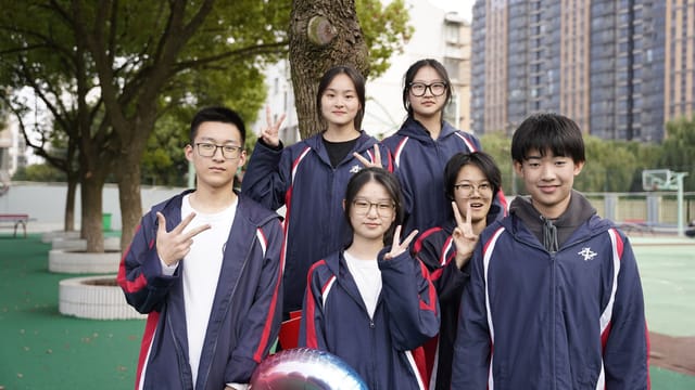 Group of Asian school children in uniforms making peace signs outdoors in Wuxi, China.