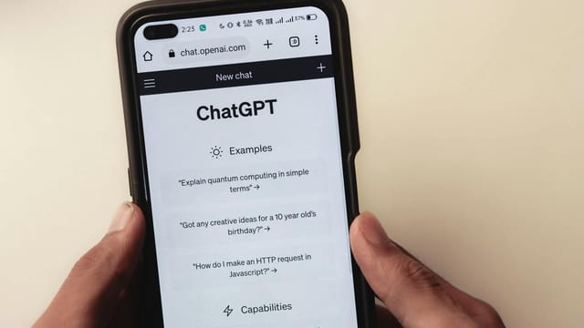 Close-up of hands holding a smartphone displaying the ChatGPT application interface on the screen.