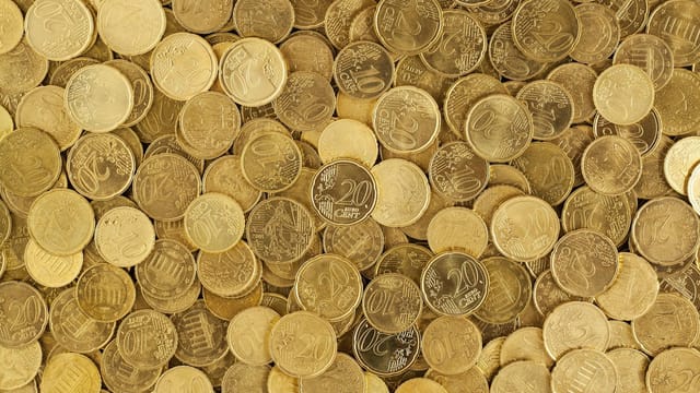 A close-up shot of Euro coins scattered in a pile, showcasing a rich golden texture.
