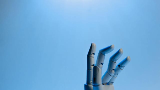 Robotic hand with articulated fingers reaching towards the sky on a blue background.
