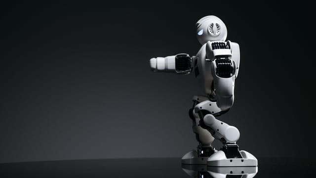 A white robot showcasing modern design on a sleek dark surface.