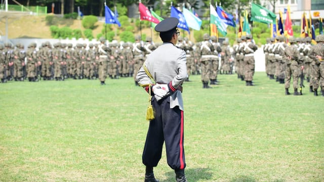 A military officer oversees a formation during a vibrant outdoor ceremony.