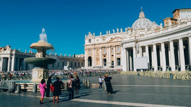 St. Peter's Basilica and fountain in St. Peter's Square, Vatican City, showcasing iconic architecture and tourists.