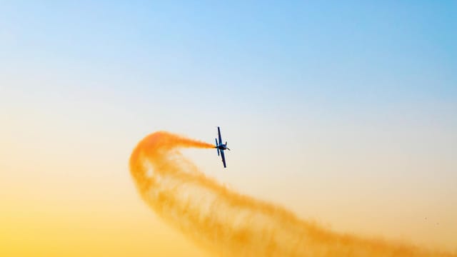 Airplane performing an aerial stunt against a vibrant sky in Dubai, UAE.