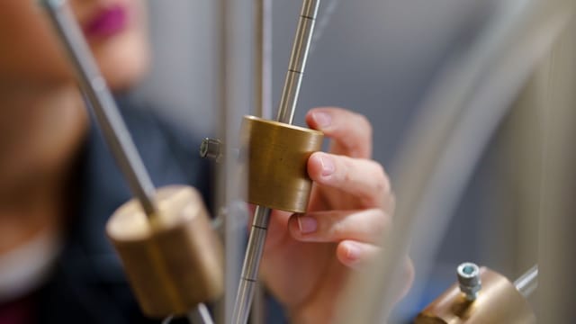 Illustrative image: A student conducting an interactive physics experiment with brass components.