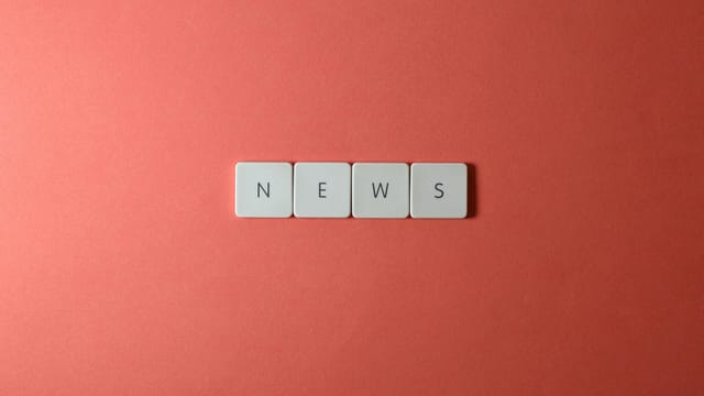 Close-up of keyboard keys spelling 'NEWS' on a red background, minimalist style.