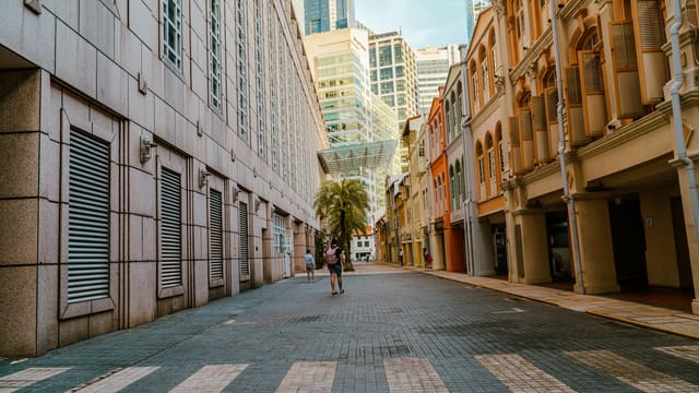 A serene empty street in Singapore's city center, showcasing modern buildings and classical architecture under a clear sky.