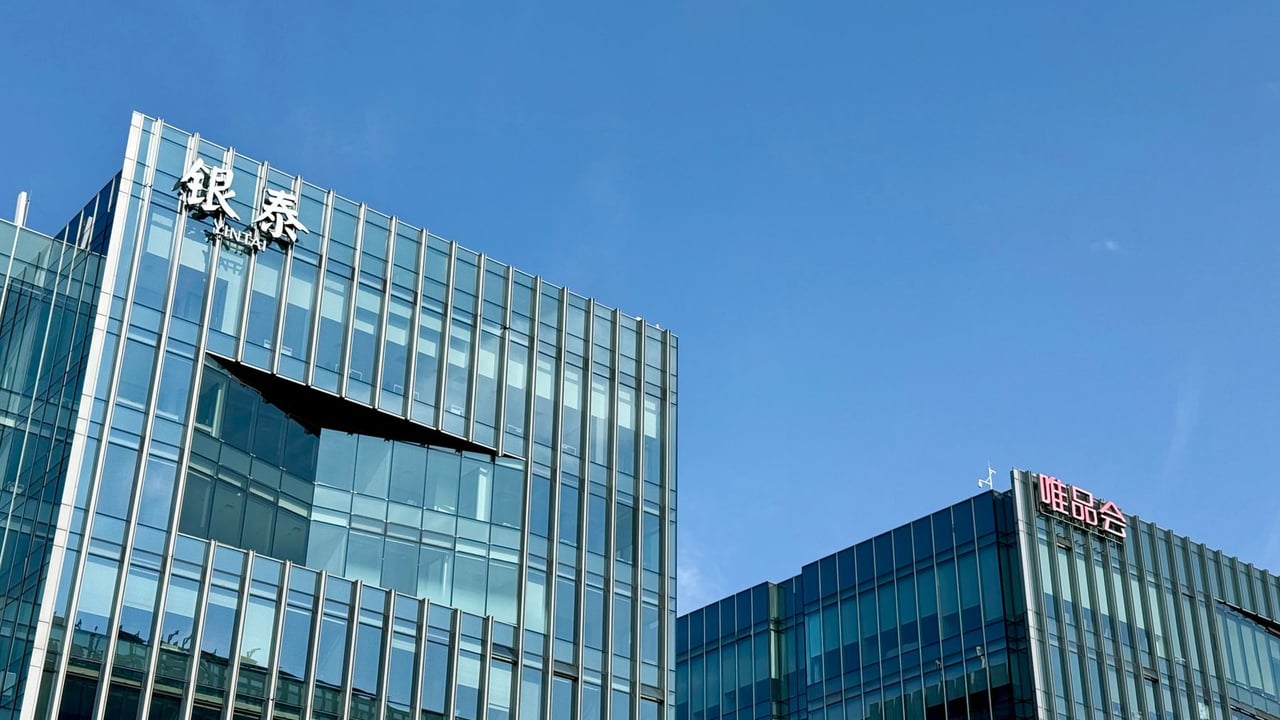 Close-up of modern glass facade buildings under a clear blue sky in Shanghai, China.