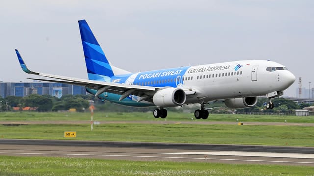 Garuda Indonesia plane taking off from a runway, showcasing modern aviation.