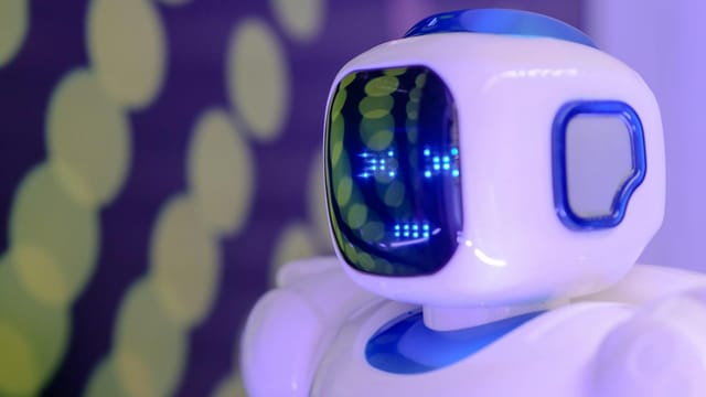 Close-up of a futuristic humanoid robot with a luminescent display in a modern setting.