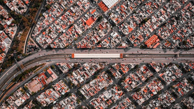 High-angle aerial view of a densely populated cityscape with a central highway.