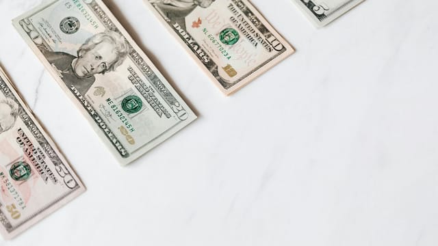 US dollar banknotes arranged on a clean white surface, showcasing different denominations.