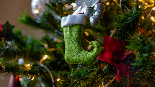 Close-up of a festive Christmas boot ornament on a decorated tree with lights.