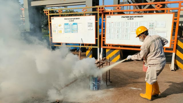 Worker conducts fire safety training outdoors with extinguishers.