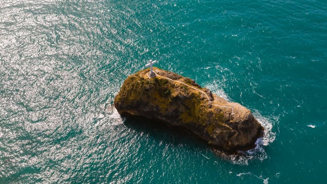 Drone captures cross atop rock in Black Sea near Sevastopol, offering a scenic coastal view.