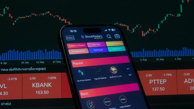 Close-up of a smartphone displaying a stock trading app against a backdrop of market charts.