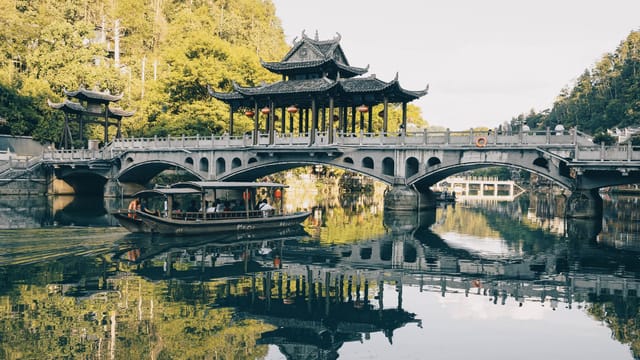 Beautiful traditional Chinese bridge over a reflective lake with lush surroundings.
