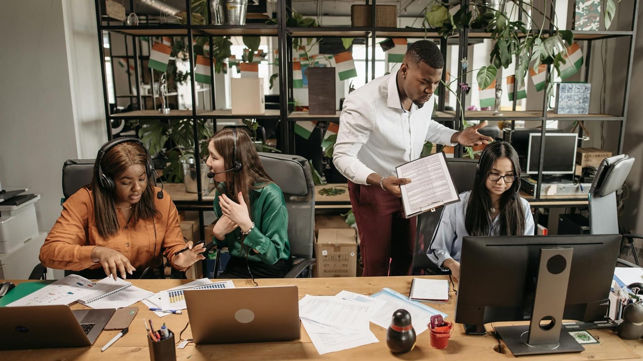A diverse team of call center agents in a lively office setting, collaborating on tasks and discussing reports.