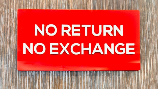 Bold red sign with 'No Return No Exchange' message on a wooden backdrop.