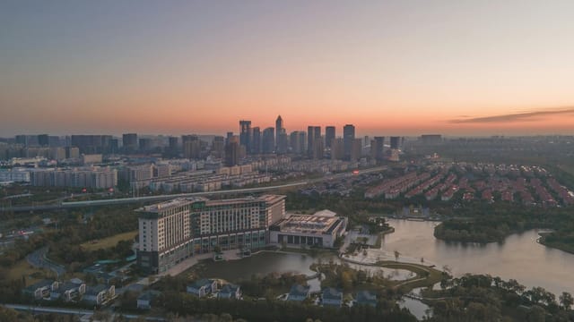 Aerial cityscape view at dawn showcasing urban buildings, parks, and water features.