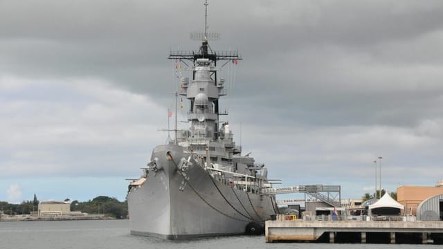 The iconic USS Missouri battleship docked at Pearl Harbor under a cloudy sky, Hawaii.