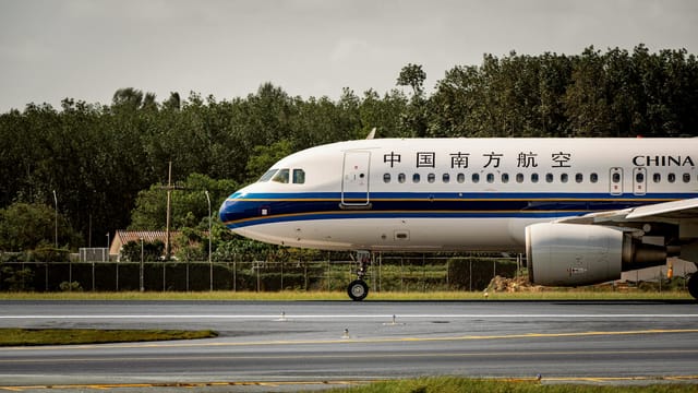 China Southern Airlines airplane on runway with green backdrop.